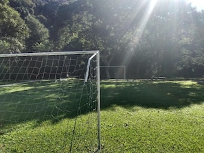 Un arco de fútbol en un campo cubierto de césped, con árboles al fondo.