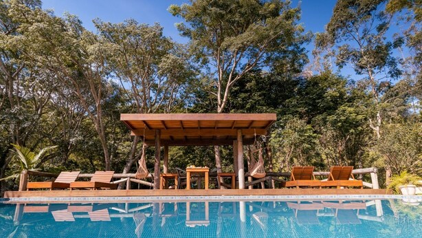 Un área de piscina con sillones de madera y una pérgola de madera.