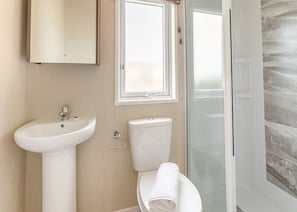 A bathroom with a sink, toilet, and shower. - Sandy Pebble Deluxe (Pet) (Looe)