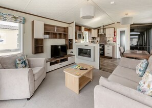 A modern living room with a flat-screen TV, sofa, coffee table, and a fireplace.