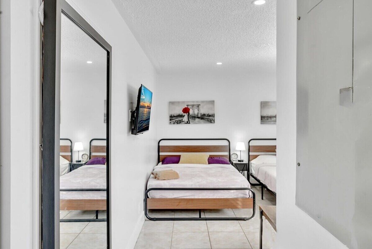A modern bedroom with two single beds, a TV, and artwork on the wall.