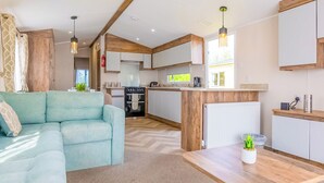 Eine moderne Küche mit weißen Schränken, einer Holzarbeitsplatte und einem Essbereich mit Tisch und Sofa.