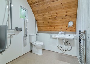 A bathroom with a wooden ceiling, a toilet, a sink, and a shower.