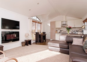 A spacious living area with a large flat-screen TV, a dining table, and a kitchen in the background. - 1 bedroom accommodation in Narberth, Nr Tenby (Narberth, Nr Tenby)