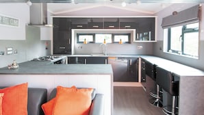 Une cuisine moderne dotée d’un îlot central, de meubles de rangement noirs et d’une grande fenêtre qui laisse entrer la lumière naturelle.
