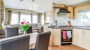 A modern kitchen with a central island, a dining area with a table and chairs, and a living room with a sofa and curtains. - 1 bedroom accommodation in Alyth, Perthshire (Alyth, Perthshire)