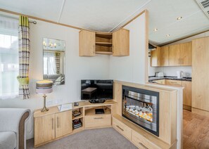 A compact living space with a TV, wooden cabinets, a fireplace, and a kitchen area.