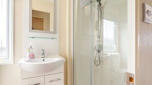 A bathroom with a white sink, a mirror, a glass shower enclosure, and a window. - 1 bedroom accommodation in Alyth, Perthshire (Alyth, Perthshire)