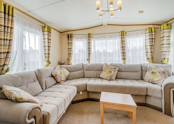 A living room with a sectional sofa, a small table, and curtains with a striped pattern.