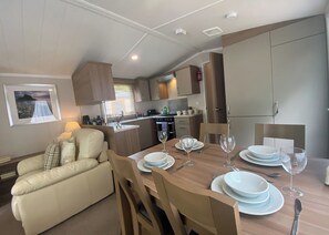 A compact living space with a dining area, kitchenette, and a sofa. - 2 bedroom accommodation in Snowdonia (Snowdonia)
