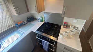 Uma cozinha compacta com fogão, forno e um pequeno balcão com torradeira e acompanhamentos.