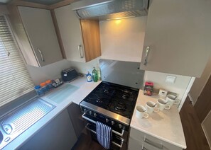 A compact kitchenette with a stove, oven, and a small countertop with a toaster and condiments.
