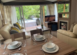 Ein Zimmer mit Esstisch für vier Personen, einer Couch, einem Fernseher und einem Kamin.