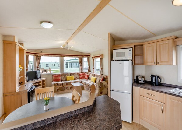 A caravan interior with a dining area, kitchen, and seating space.