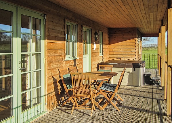 A wooden cabin with a dining area, large windows, and a covered patio.