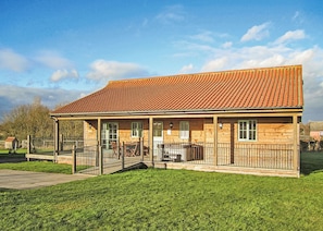 A wooden building with a tiled roof, a covered porch, and a fenced yard.