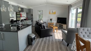 A modern kitchen with a dining area, a sofa, a TV, and a window with a view. - 1 bedroom accommodation in Hawes, (Hawes,)