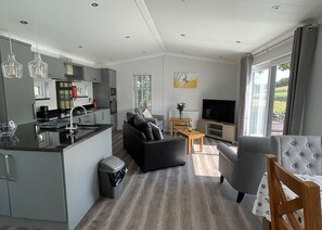 A modern kitchen with a dining area, a sofa, a TV, and a window with a view. - 1 bedroom accommodation in Hawes, (Hawes,)