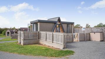 Un bâtiment moderne doté d’un toit en pente, de clôtures en bois et d’une allée gravillonnée.