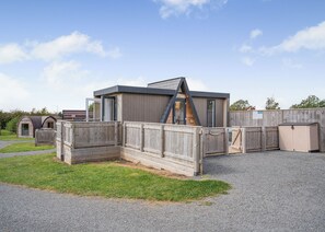 A modern building with a sloped roof, wooden fences, and a gravel driveway.