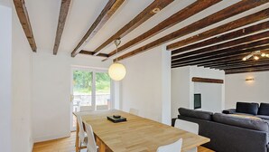 Un área de comedor con una mesa y sillas de madera, un sofá y un techo con vigas a la vista.
