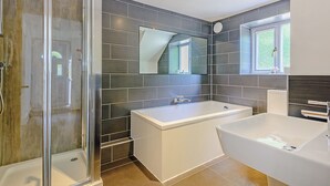 Un baño moderno con cabina de ducha de vidrio, bañera independiente y lavamanos aparte.