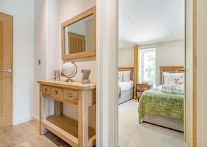 A bedroom with a wooden dresser, a mirror, a globe, and a bed with a green blanket.