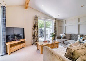 A living room with a TV, wooden furniture, a sofa, and a view through a glass door. - 2 bedroom accommodation in Cannington (Cannington)