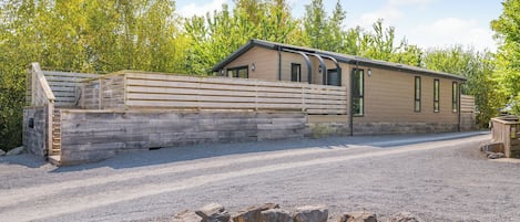 A single-story building with a wooden fence, a gravel driveway, and a stone wall.