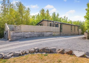 A single-story building with a wooden fence, a gravel driveway, and a stone wall.
