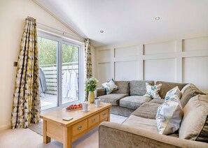 A living room with a sofa, a coffee table, and a window with curtains.
