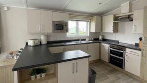 Eine moderne Küche mit schwarzem Arbeitsplatz, weißen Schränken, einer Mikrowelle, einem Backofen und einem Spülbecken.
