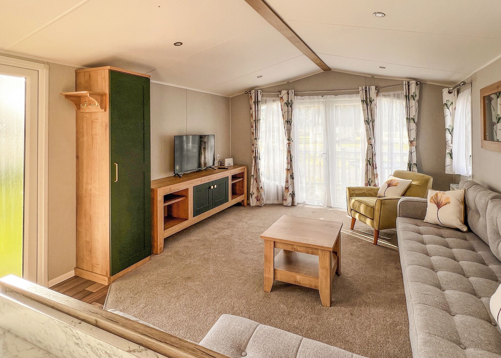 Ein Wohnzimmer mit einer Couch, einem Couchtisch, einem Fernseher auf einem Holzgestell und einer grünen Tür.