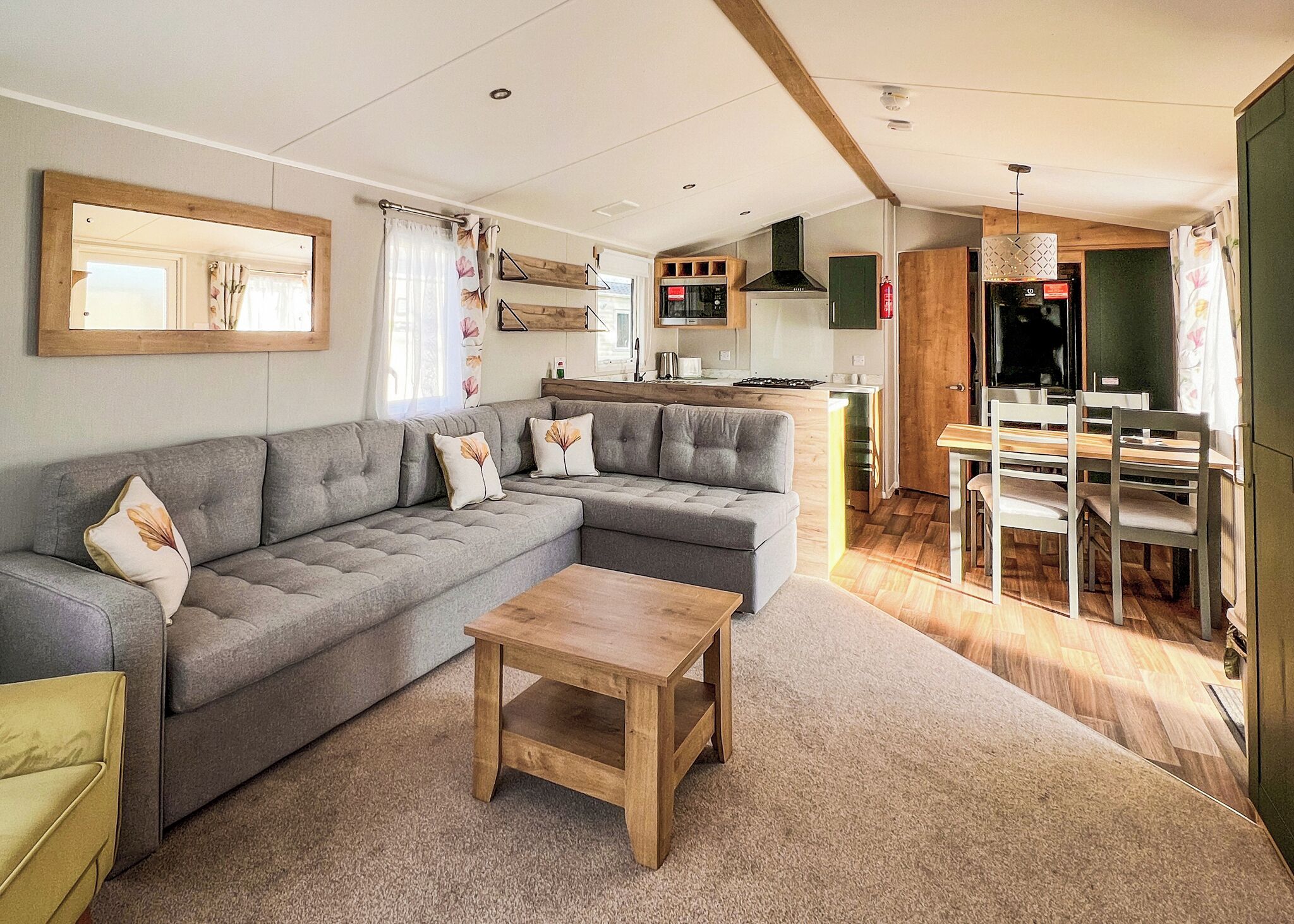 Een moderne woonkamer met een grijze modulaire bank, een houten salontafel, en een eethoek met een houten tafel en stoelen.