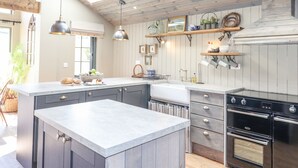 A modern kitchen with a large island, wooden ceiling, and built-in appliances. - The Owl's Shack (Kendal)