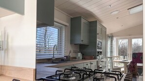 Ett modernt kök med en gasspis, en diskho och ett fönster med persienner.
