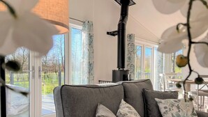 Ett modernt vardagsrum med en soffa, kuddar, ett bord och ett stort fönster.