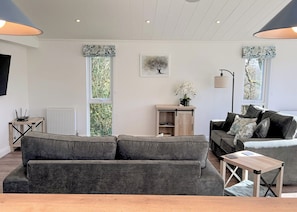 A living room with a grey sofa, a wooden coffee table, a lamp, and a radiator.