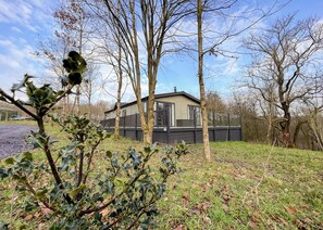 A house with a deck, surrounded by trees and grass.
