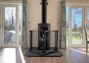 A modern room with a wood-burning stove, large windows, and a view of the outdoors.