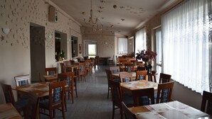 A spacious dining area with multiple tables and chairs, a chandelier, and decorative ceiling elements. - Willa Białe Piaski (Krokowa)