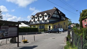 A yellow building with a dark roof, multiple windows, and a signboard. - Willa Białe Piaski (Krokowa)