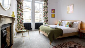 A bedroom with a bed, a chair, a fireplace, and a view of the city through large windows. - Stunning one bed apartment in central location - Pass the Keys (Bath)