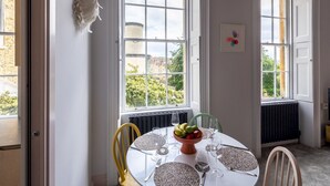A dining room with a round table set for four, large windows, and a swan decoration on the wall. - Stunning one bed apartment in central location - Pass the Keys (Bath)