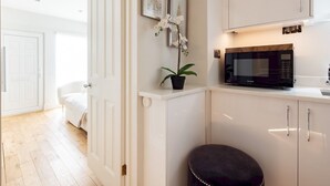 A modern kitchen with white cabinetry, a black microwave, and a potted orchid. - Chic Apartment, Steps away from King's Rd Chelsea - Pass the Keys (London)