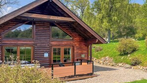 Une cabane en bois avec un toit en pente, de grandes fenêtres et une allée gravillonnée.