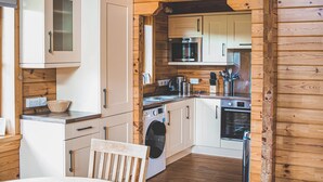 Une cuisine compacte avec des murs en bois, un lave-linge, un four à micro-ondes et un évier.