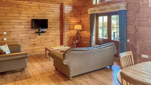 Un intérieur en bois comprenant un canapé, une table, une lampe, un téléviseur et une fenêtre donnant sur un beau paysage.