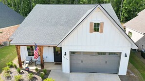A single-story house with a garage, a small porch with chairs, and an American flag. - Lots of amenities. Open Floor plan. Perfect for families and groups!  (Auburn)