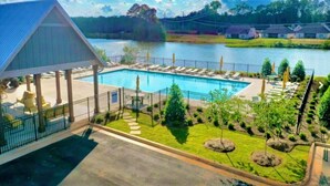 A swimming pool with lounge chairs, a covered pavilion, and a view of a lake and buildings in the background. - Lots of amenities. Open Floor plan. Perfect for families and groups!  (Auburn)